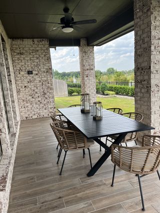 A cozy patio with wicker seating, a sleek black table, and serene views, perfect for outdoor dining and relaxation.