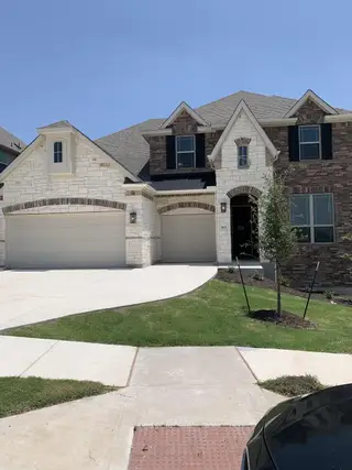 A beautiful two-story home with stone and brick accents in Retreat at San Gabriel by Brightland Homes (Georgetown, TX).