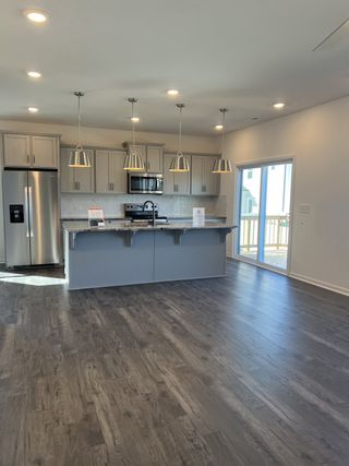 A modern kitchen featuring sleek gray cabinets, elegant pendant lights, and stainless steel appliances.