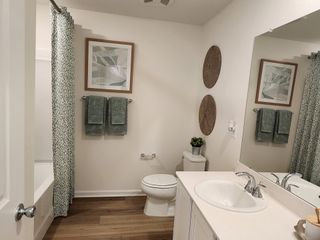 A cozy bathroom with wood floors, a modern sink, stylish decor, and green accents for a refreshing look.