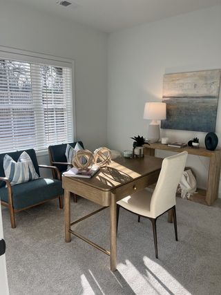 Model Home A bright home office with elegant wooden furniture, cozy chairs, and soft natural lighting creating a serene workspace.