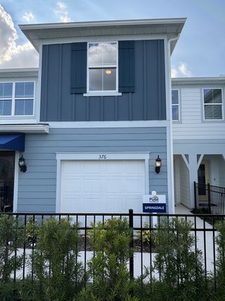 A stylish two-story townhome with blue and white siding, black shutters, and a fenced front yard in Emerald Pointe by Pulte Homes (Apopka, FL).