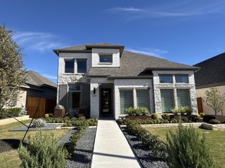 A charming white brick home with modern design and lush landscaping in Lariat 50' by Perry Homes (Liberty Hill, TX).