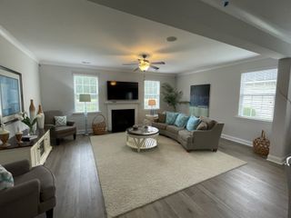 A cozy living room features elegant seating, a fireplace, and abundant natural light, creating a welcoming ambiance.