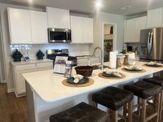A modern kitchen with sleek white cabinets, a spacious island, and stainless steel appliances.