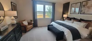 A cozy bedroom with a plush bed, elegant decor, and a stylish armchair, complemented by soft lighting and natural tones.