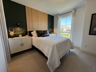 A cozy bedroom featuring a wood accent wall, a large window, and modern decor.