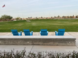 Relax in blue chairs overlooking a spacious green park at Highland Ridge at Alamar by Brookfield Residential (Avondale, AZ).