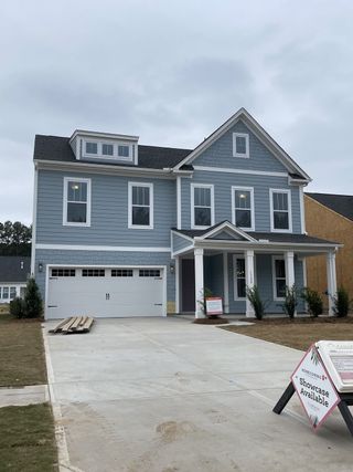 A beautiful blue home with crisp white trim and a spacious driveway in Homecoming by True Homes (Ravenel, SC).