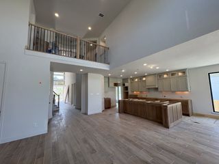 Model Home An open-concept kitchen and living space with high ceilings and modern wood flooring in Johnson Ranch by Perry Homes (Bulverde, TX).