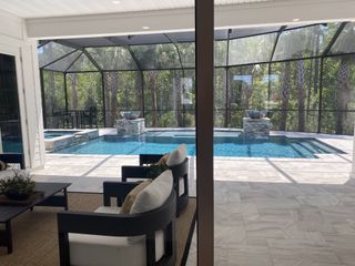Luxurious screened-in pool area with modern seating, elegant tiles, and serene views of lush surroundings.