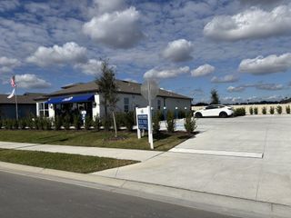 A contemporary sales center with a blue canopy in Twisted Oaks by Pulte Homes, Wildwood, FL, with landscaped surroundings.