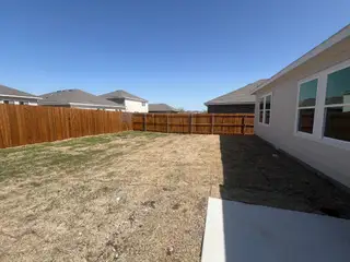 Spacious backyard with wooden fencing and a charming side view in the Ranch at Duck Creek by Starlight Homes (Fort Worth, TX).