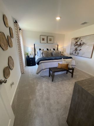 Model Home A cozy bedroom with a plush bed, textured decor, and elegant artwork, offering a serene and inviting atmosphere.
