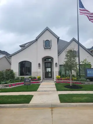 A beautiful modern white brick home with lush landscaping in The Tribute 50' by Britton Homes (Frisco, TX).