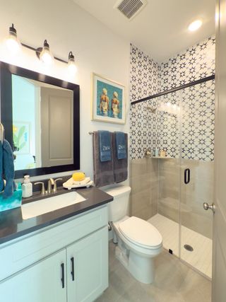 Model Home A modern bathroom featuring a glass shower with patterned tiles, sleek vanity, and stylish lighting.