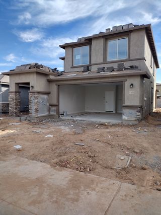A modern two-story home under construction at Allen Ranches by Pulte Homes in Litchfield Park, AZ, with stone accents and a spacious garage.
