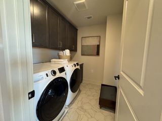 A functional laundry room with modern appliances, sleek cabinetry, and stylish tile flooring.