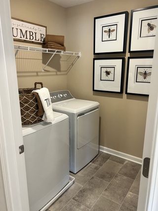 A modern laundry room with neatly framed wall art, practical shelving, and a cozy farmhouse aesthetic.