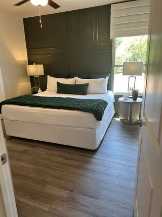 A cozy bedroom featuring a dark accent wall, elegant lighting, and sleek flooring for a stylish retreat.