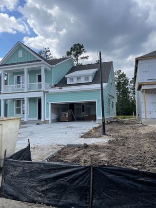 A charming under-construction teal home with a balcony in Tidewater at Lakes of Cane Bay by Dream Finders Homes (Summerville, SC).