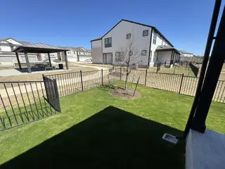 Model Home Lush green backyard with a private fence and a charming tree, offering space for outdoor activities and leisure.