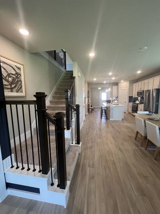 Model Home A modern interior featuring a spacious hallway with wooden flooring, elegant staircase, and chic kitchen-dining area.