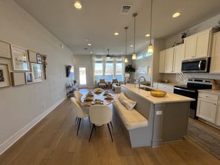 An open-concept kitchen and dining area with sleek lighting, wooden floors, and modern decor creating a warm, inviting atmosphere.