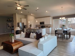 An open-concept living area with modern kitchen, cozy dining, and plush seating, featuring warm lighting and elegant decor.