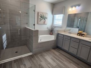 A modern bathroom with a glass shower, gray cabinetry, and elegant décor.