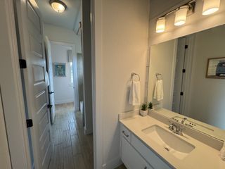 A bright bathroom with a sleek vanity, white cabinetry, and modern lighting.