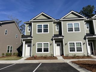 Street view Charming green townhome with white trim and manicured landscaping in Twin Rivers Towns by Prosperity Builders (Charleston, SC).