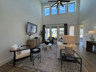 An elegant living room with high ceilings, large windows, cozy seating, and modern decor.