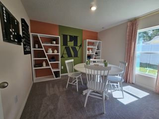 A vibrant playroom featuring an accent wall with "PLAY" art, white shelves, and ample natural light from a large window.