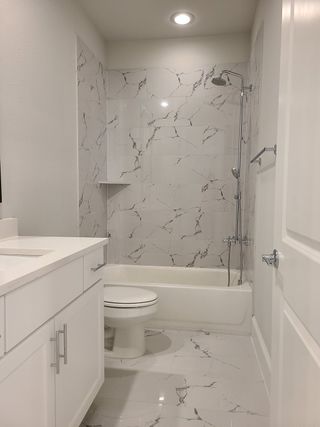 A modern bathroom featuring marble-patterned tiles, sleek countertops, and elegant fixtures for a luxurious feel.