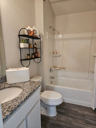 Model Home A cozy bathroom with a granite countertop, modern fixtures, and stylish shelving for decor.