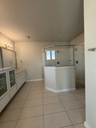 Model Home A modern bathroom with a large glass shower, dual vanities, and sleek tile flooring.