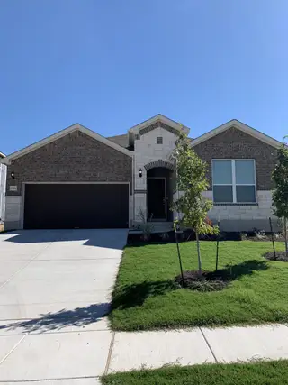 Street view A charming brick home with pristine landscaping in Lagos by Pulte Homes (Manor, TX).