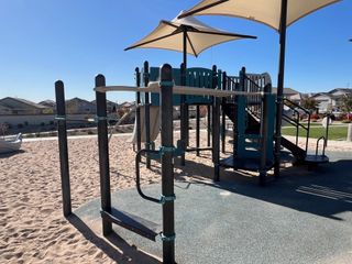 Community Amenities A modern playground with shade sails in Northern Farms by Landsea Homes, Waddell, AZ, surrounded by a sandy landscape.