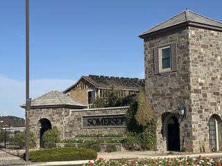 Community Amenities A grand stone entrance welcomes residents to Atrium at Somerset by Capital West Homes in Gilbert, AZ, with lush landscaping and timeless design.