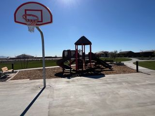 A vibrant playground and basketball hoop in Windrose by Brightland Homes, offering family-friendly spaces in Waddell, AZ.
