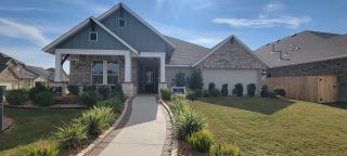 Street view A charming craftsman-style home with stone and brick accents in The Reserve at Weston Oaks by David Weekley Homes (San Antonio, TX).
