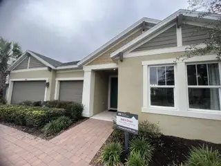 A charming home with a blend of stone and stucco, a welcoming front porch, and beautiful landscaping at River Landing by Taylor Morrison (Wesley Chapel, FL).