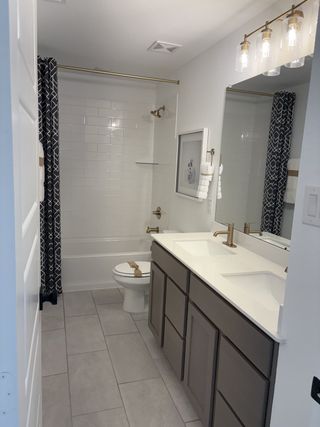 A sleek bathroom featuring a double vanity, modern fixtures, and a stylish patterned shower curtain.