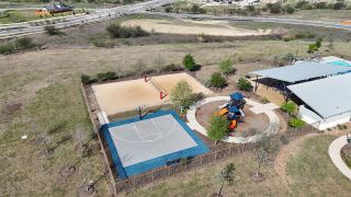 Community Amenities A vibrant recreational area featuring a basketball court, sand volleyball court, and playground in TRACE by Terrata Homes (San Marcos, TX).