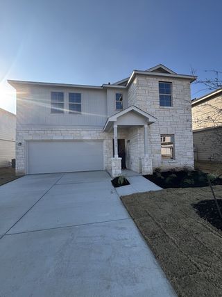Model Home A modern two-story home with stone and siding exterior, a covered entry, and a two-car garage in Blue Ridge Ranch by M/I Homes (San Antonio, TX).