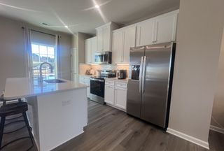 A modern kitchen featuring stainless steel appliances, white cabinetry, and an island with seating.