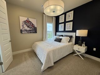 Model Home A cozy bedroom with a statement cat painting, modern lighting, and a contrasting dark accent wall.