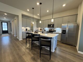 A modern kitchen with sleek cabinetry, stainless steel appliances, and a large island with pendant lighting.