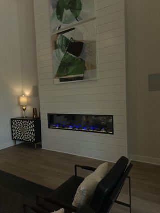 A modern living room featuring a sleek linear fireplace, abstract art, and stylish seating for a chic ambiance.